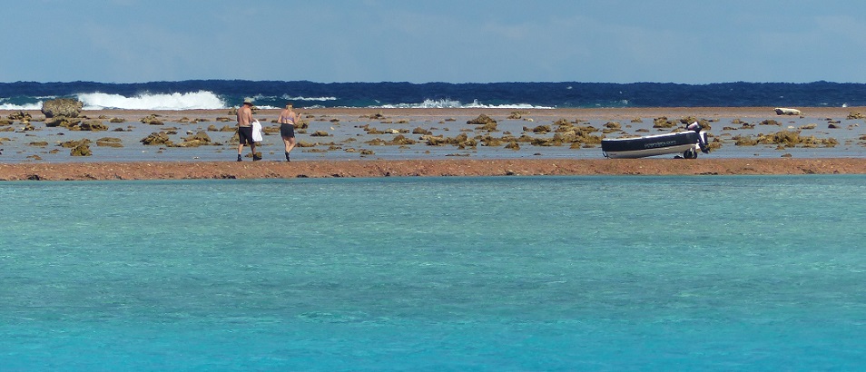 Chuck and Lauri walk to their dinghy on Minerva Reef